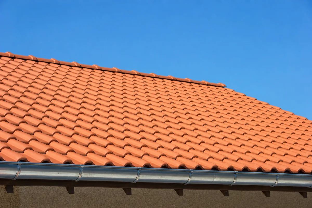 Toiture propre après démoussage, tuiles nettes et gouttière dégagée sous un ciel clair